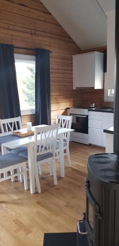 y cocina con mesa, sillas y fogones. en Ammeråns Fiskecamp en Hammarstrand