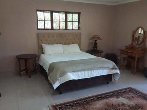 1 dormitorio con 1 cama con 2 mesas y una ventana en The Court House- Ramsgate KZN en Ramsgate