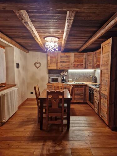 a kitchen with wooden cabinets and a table and chairs at Suite ad Antagnod in Champoluc