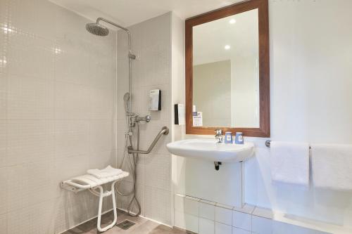 W łazience znajduje się prysznic, umywalka i lustro. w obiekcie Kyriad Brie-Comte-Robert w mieście Brie-Comte-Robert