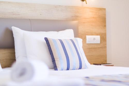 a white bed with a blue and white pillow at Theo Star Beach Hotel in Malia