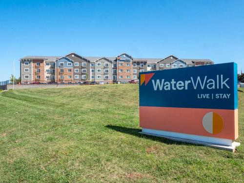 un letrero de paseo de agua en un campo frente a un edificio en Waterwalk Charlotte Arrowood en Charlotte