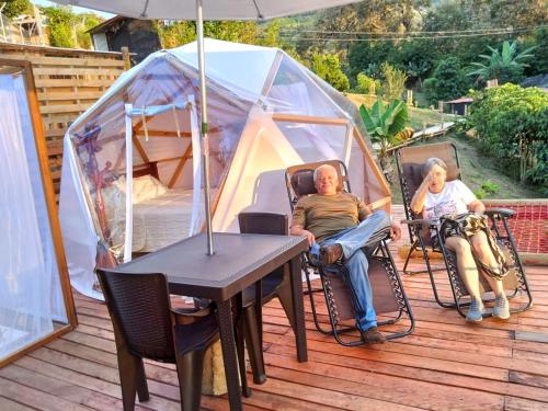 dos personas sentadas en una terraza frente a una tienda en Glamping Sant Sebastian, en Tuluá