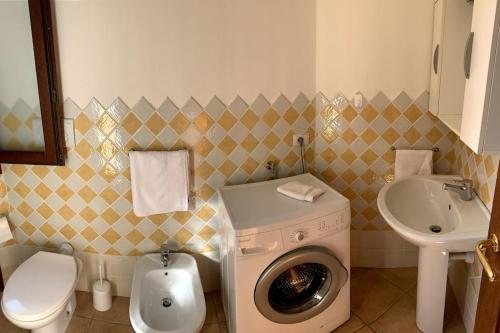 uma casa de banho com uma máquina de lavar roupa e um lavatório em Holiday home Villetta La Cruzitta em Costa Paradiso