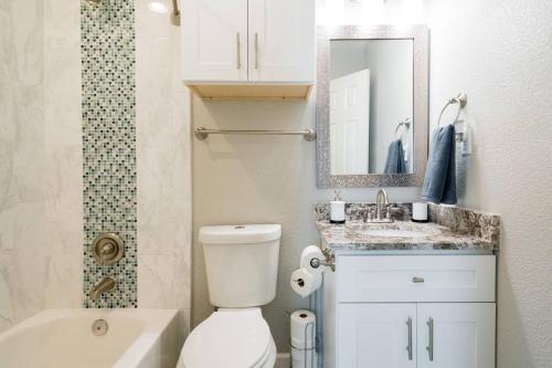 a bathroom with a toilet and a sink and a mirror at Peaceful and Relaxing Getaway w Beautiful Pool in Richardson