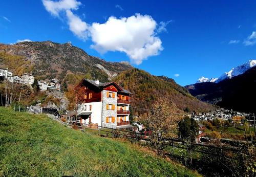 a building on a hill with mountains in the background at ALPINO B&B in Chiesa in Valmalenco