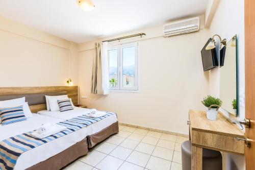 a bedroom with a bed and a desk and a window at Theo Star Beach Hotel in Malia