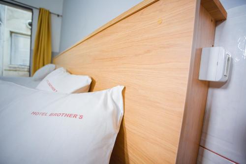 1 cama con cabecero de madera y almohada blanca en Hotel Brothers São Paulo - 3km do Hospital das Clínicas FMUSP, proximo a Universidades - By UP Hotel en São Paulo