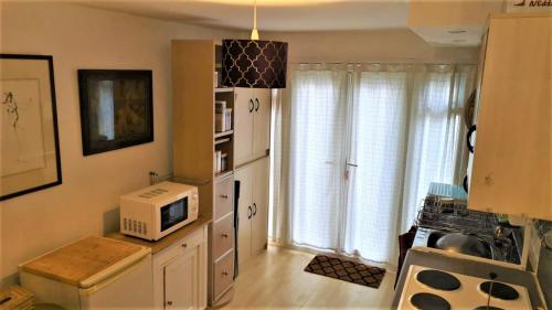 a kitchen with a microwave on a counter and a window at 1 Dbl Bed Ground Floor Modern Oriental Flat Greenwich Park in London