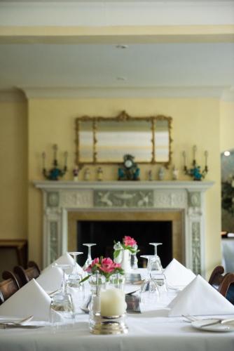 a table with a white table cloth and a fireplace at Plumber Manor Hotel in Sturminster Newton