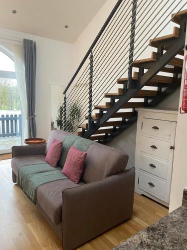 a couch in a living room with a staircase at Rossendale Holiday Cottages & Spa in Rossendale