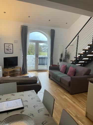 a living room with a couch and a staircase at Rossendale Holiday Cottages & Spa in Rossendale