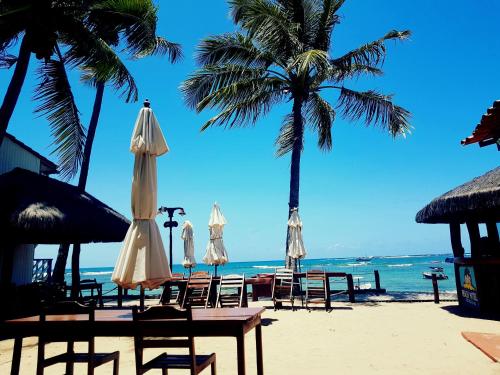 a beach with chairs and umbrellas and the ocean at Morro Beach Hotel in Morro de São Paulo