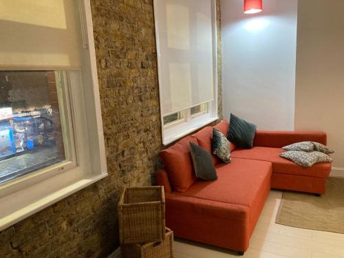 a living room with a red couch and a window at Goswell Central Apartment by DC London Rooms in London