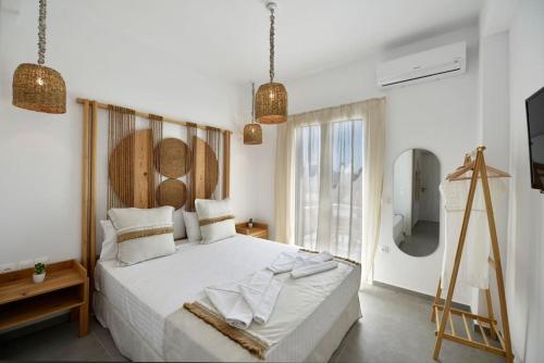 a bedroom with a large white bed and a window at Kryni Deluxe Houses in Adamas