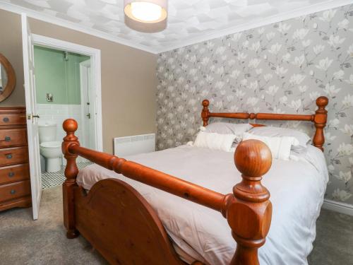 a bedroom with a wooden bed and a wall with butterflies at Cedars in Holyhead