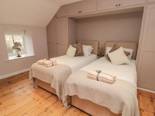 two beds in a bedroom with wooden floors and a window at Donni Hall Cottage in Chathill