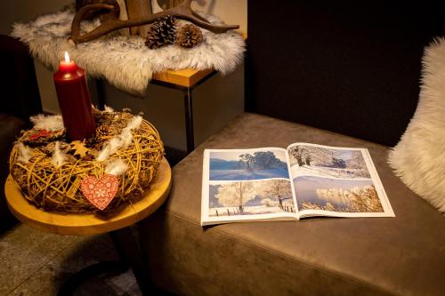 a table with a book and a red candle and a candle at Emma Deluxe Aparthotel ganzjährig beheizter Außenpool in Piesendorf