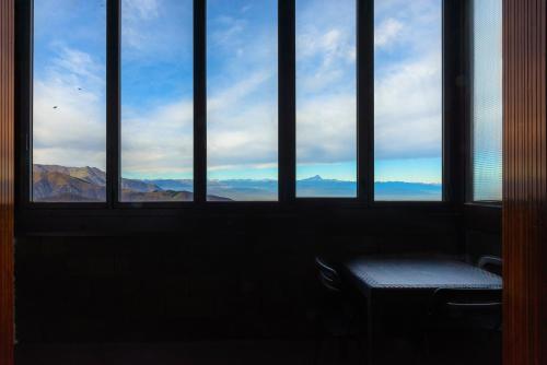 a room with four windows with a view of the mountains at Appartamenti i Portici in Prato Nevoso