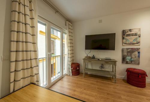 a living room with a television and a table and a window at Wide with beautiful kitchen 2Bd 3Bth -Arenal in Seville