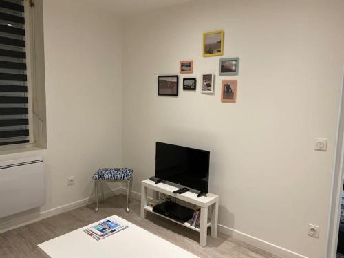 a living room with a tv on a white wall at Bel appartement avec jardin au coeur d'Etretat in Étretat