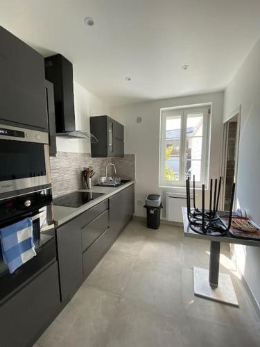 une cuisine avec un évier et une cuisinière four supérieur dans l'établissement Bel appartement avec jardin au coeur d'Etretat, à Étretat