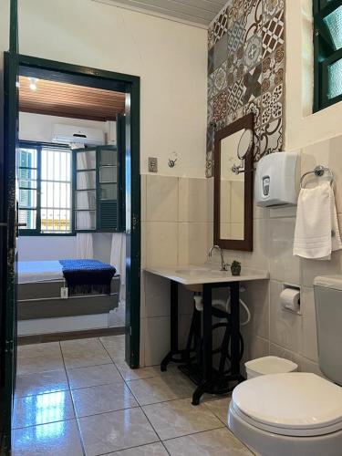 a bathroom with a toilet and a sink and a mirror at Mala & Tudo Pousada in Torres