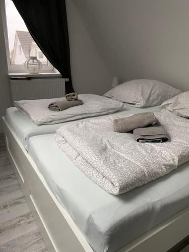 two beds with white sheets and towels on them at Gästehaus Bönebüttel-nahe Neumünster Netflix in Bönebüttel