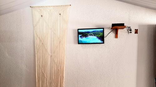 a tv hanging on a wall with alevision at FLATS VASCONCELOS in Itacaré