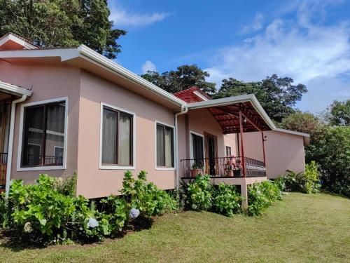 une maison rose avec un balcon dans l'établissement Monteverde House, à Monteverde Costa Rica
