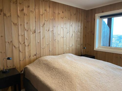 a bedroom with wooden walls and a bed and a window at Perfect Christmas atmosphere! Beautiful Apartment at Skagahøgdi with Panoramic View in Gol