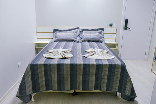 a bedroom with a bed with a blue and green striped blanket at GUARANY HOTEL PONTA PORÃ in Ponta Porã