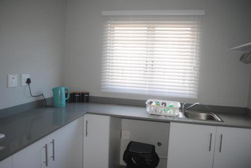 a kitchen with white cabinets and a sink and a window at Barefoot Bungalo in Amanzimtoti