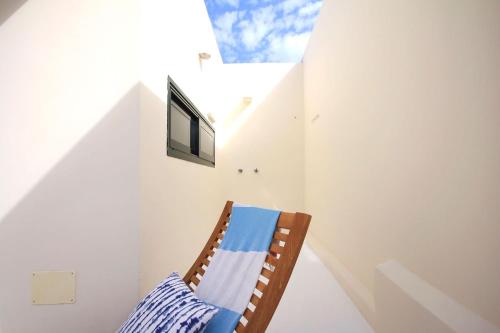 Habitación blanca con silla y ventana en Unique, Stylish & Calm Los Peces by the Sea, en Costa Teguise