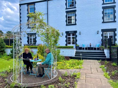 a man and woman sitting at a table in a metal structure at Eagle House - award winning luxury B&B and Apartment in Eccleshall