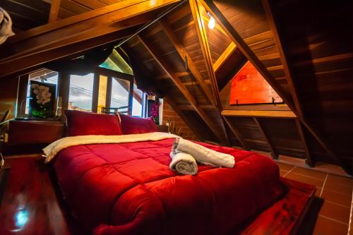 a bedroom with a red bed in a attic at Hotel Le Chateau Guatape in Guatapé