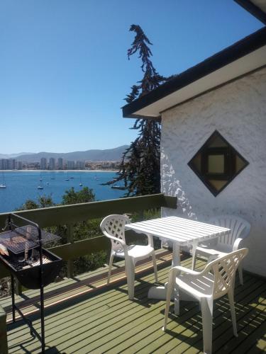 a table and chairs on a deck with a view of the water at Mistral La Herradura in Coquimbo