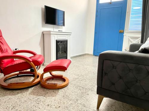 sala de estar con 2 sillas rojas y TV en Blue Levant Guest House, en Famagusta