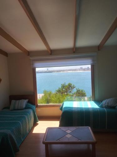 a room with two beds and a large window at Mistral La Herradura in Coquimbo