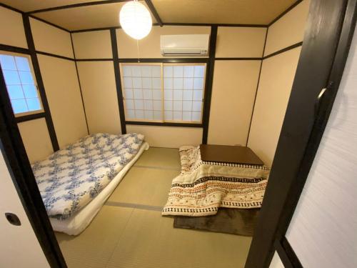 a small room with two beds and a window at WUMETEI Japanese-style lodge in Kyoto