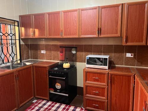 a kitchen with wooden cabinets and a microwave on a stove at Delornya Complex in Freetown