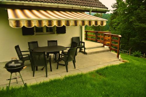 a patio with a table and chairs and a grill at Le Joly Chalet in Saint-Imier