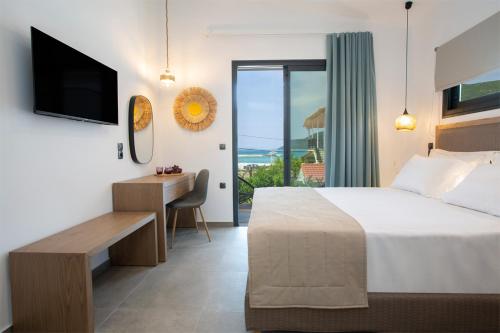 a bedroom with a bed and a desk and a television at SEASCAPE VILLAS VASSILIKI - Beachfront villas in Vasiliki