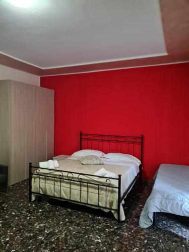 a bedroom with a red wall and two beds at Affittacamere airport orio Bergamo in Orio al Serio