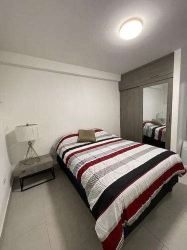 1 dormitorio con cama, lámpara y espejo en Hermosa suite en el centro Histórico de Guayaquil, en Guayaquil