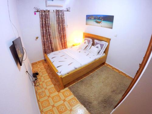 - une petite chambre avec un lit et une télévision dans l'établissement TrierHouse, à Douala