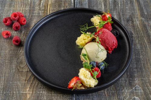 a black plate with strawberries on a wooden table at Le Baluchon Éco-villégiature in Saint-Paulin