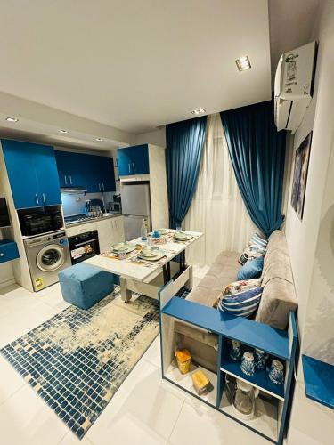 a kitchen with blue curtains and a couch and a table at Luxury Studio House 589-2 in 6th Of October