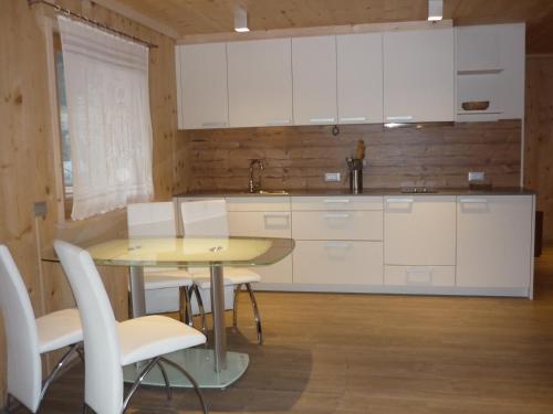 a kitchen with white cabinets and a table and chairs at Apartments Resi in Rasùn di Sotto