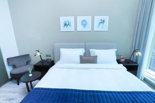 ein Schlafzimmer mit einem großen weißen Bett und einem Stuhl in der Unterkunft Damac Maison Prive Deluxe Studio with Burj-khalifa view in Dubai